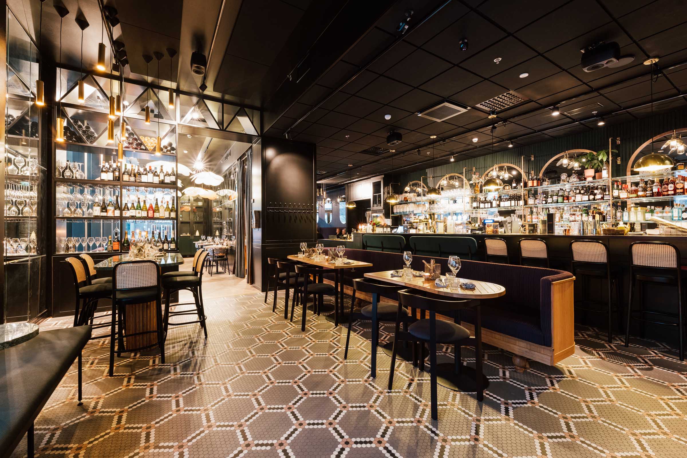 Ravintola Alfred Kitchen & Bar, sisääntulon näkymä ravintolasaliin, kuvioitu mosaiikkilattia, pöytäryhmät ja baaritiski.